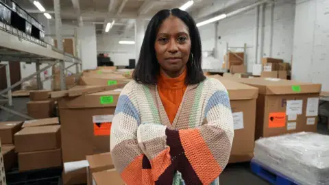 Sherrill Mosee with MinkeeBlue handbags in a warehouse,