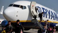 Passengers disembarking from a Ryanair plane under a cloudy sky