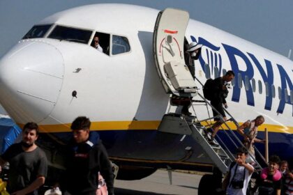 Passengers disembarking from a Ryanair plane under a cloudy sky