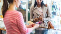 A woman pays for goods in a shop using a debit card | Trump's tariffs