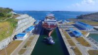 Cargo ship navigating the Panama Canal with tugboat assistance