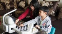 Eight-year-old Timmy playing chess with an AI robot on a Beijing apartment table. China AI