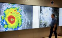 NOAA staff inspecting a satellite image of Hurricane Beryl, symbolizing the agency’s role in storm tracking